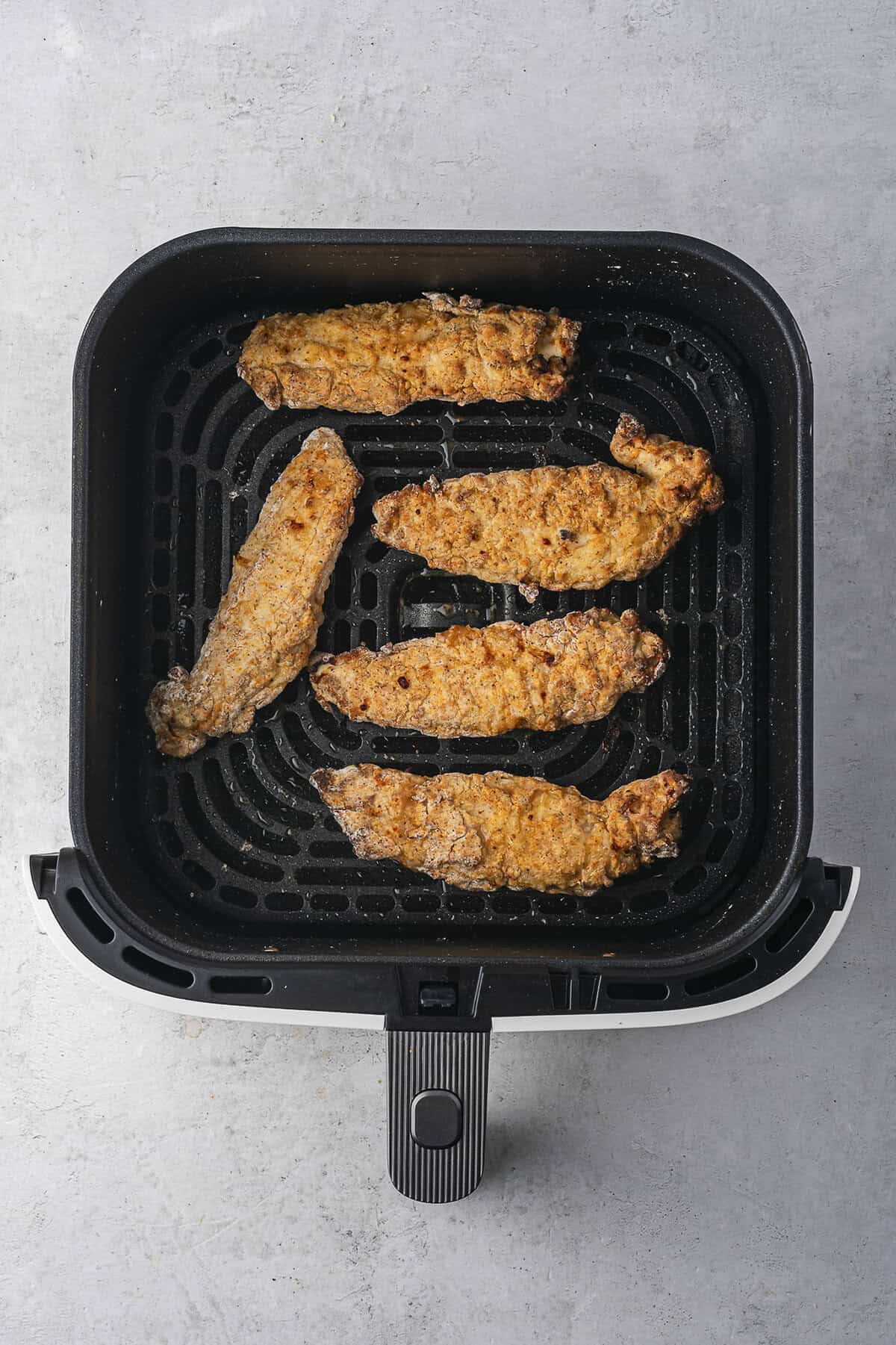 Buttermilk chicken tenders in air fryer basket.
