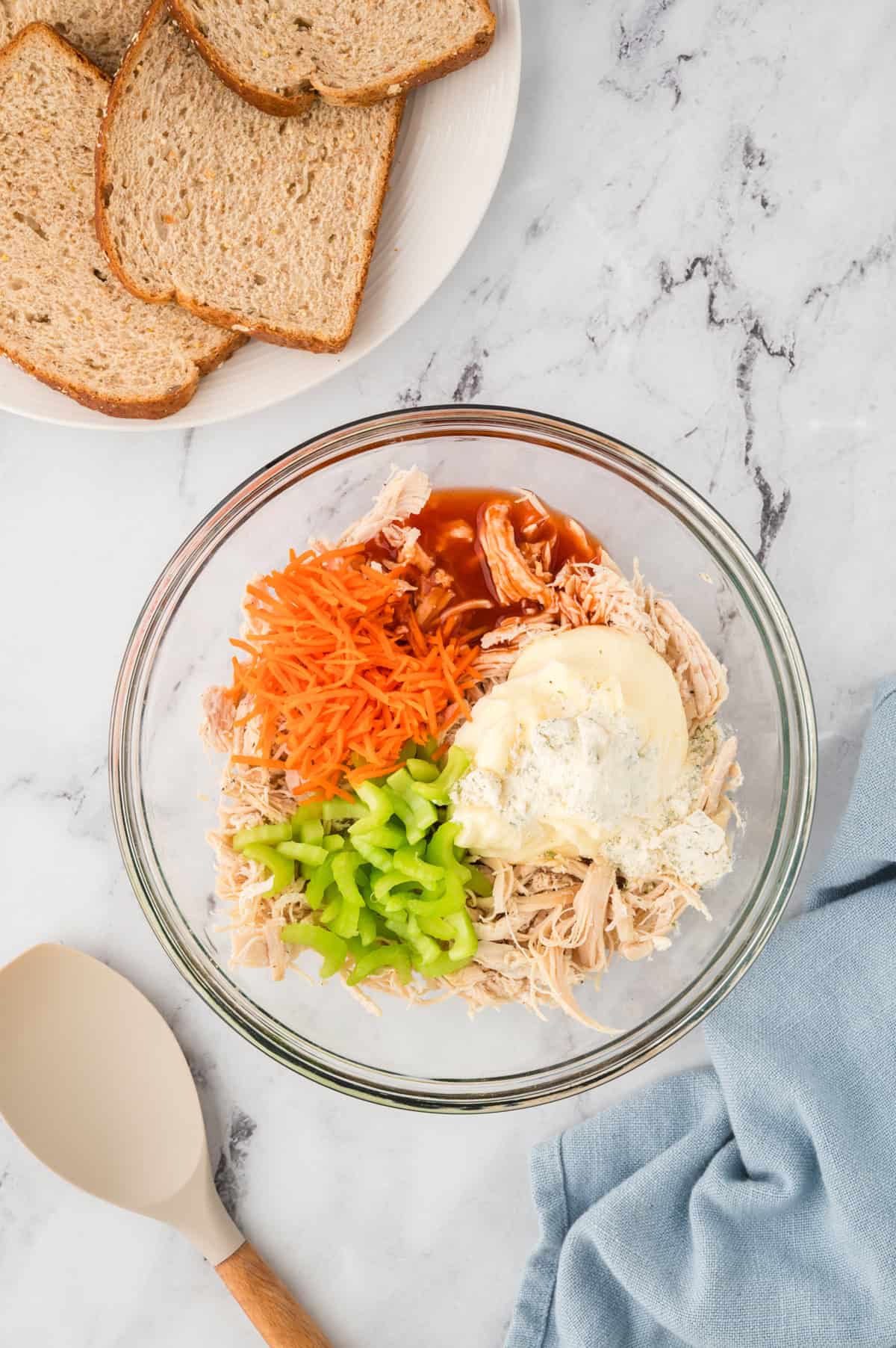 Ingredients for buffalo chicken salad in glass mixing bowl.