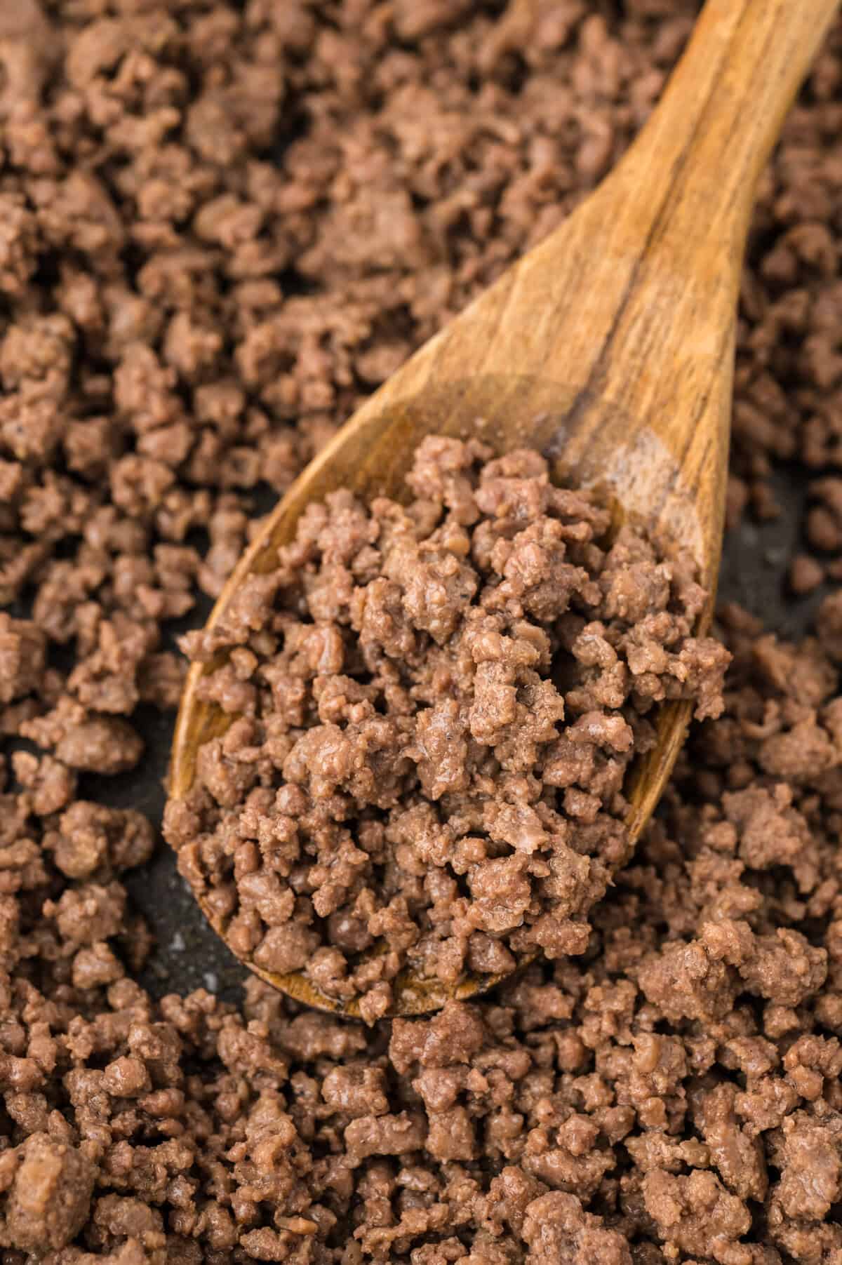Browned beef on wooden spoon.