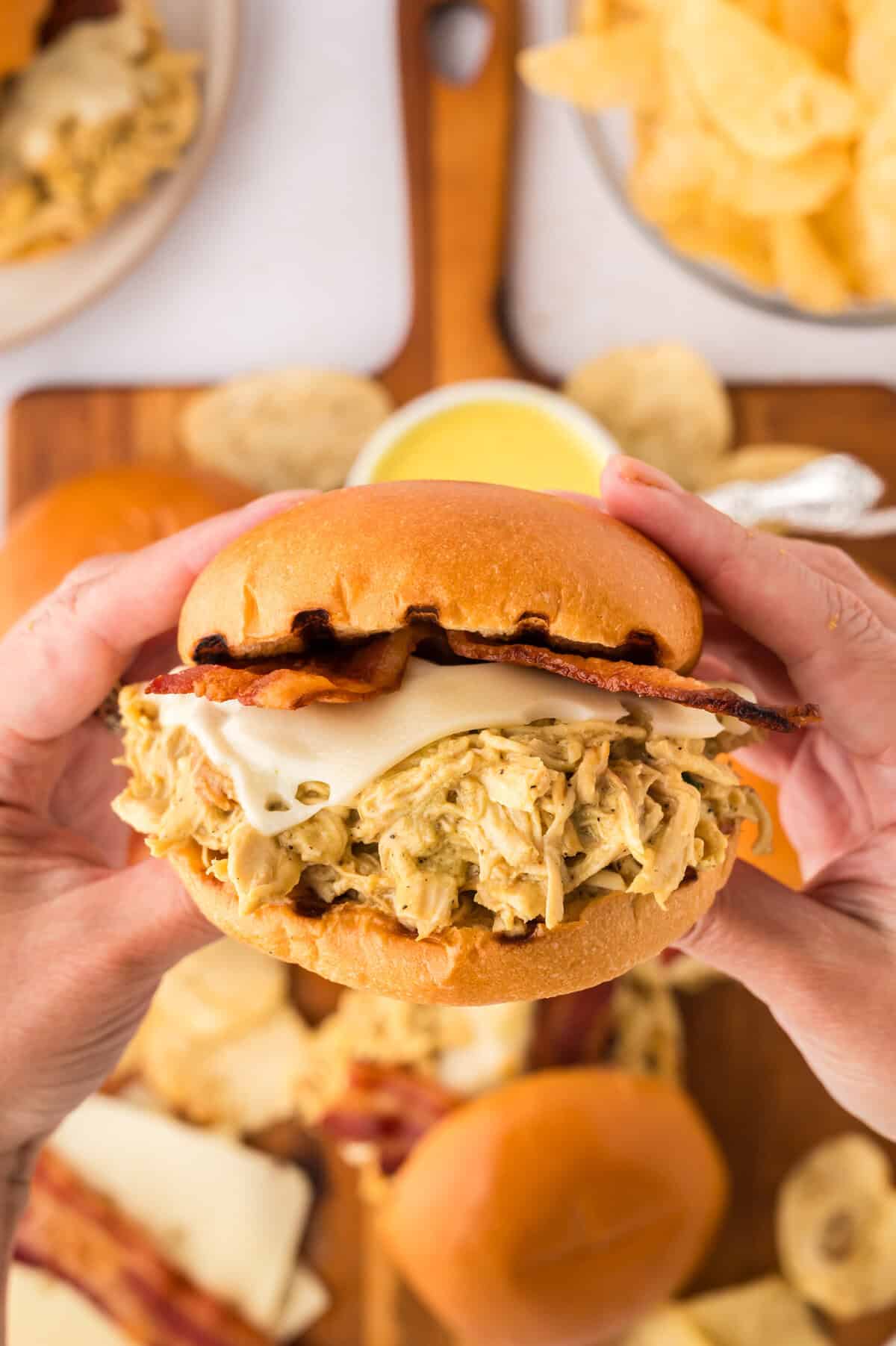 Hand holding a crockpot honey mustard chicken sandwich.