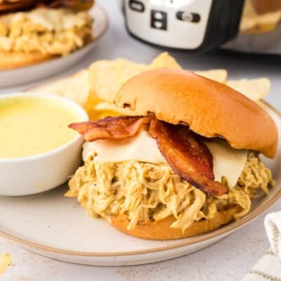 Slow cooker honey mustard chicken sandwich on white plate.