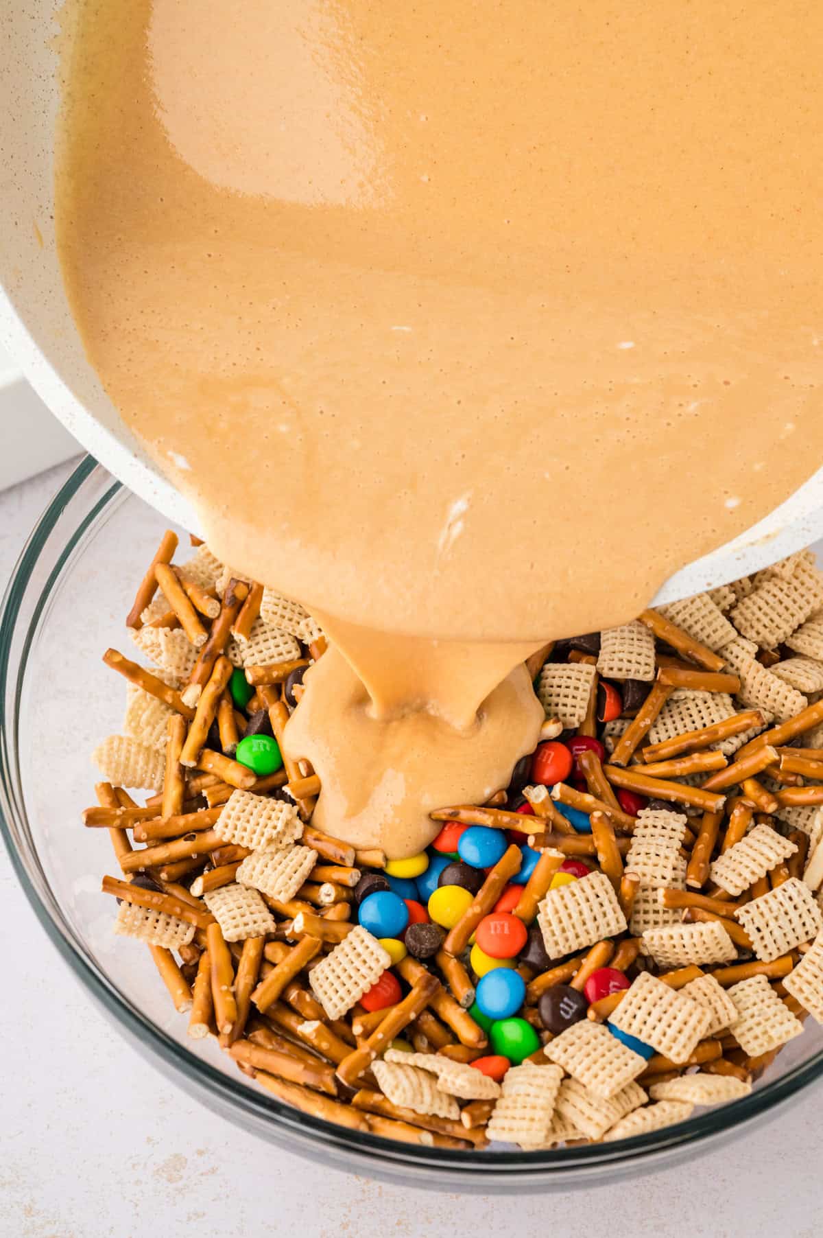 Marshmallow goo being poured over pretzels and cereal.