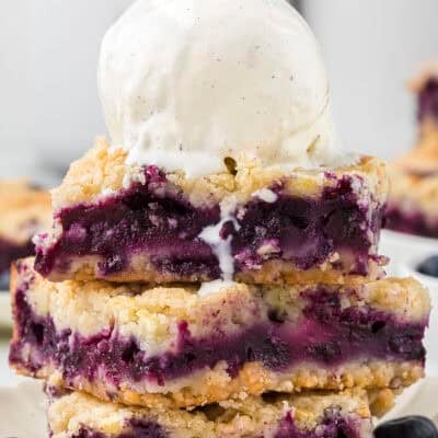 Blueberry pie bars topped with a scoop of vanilla ice cream.