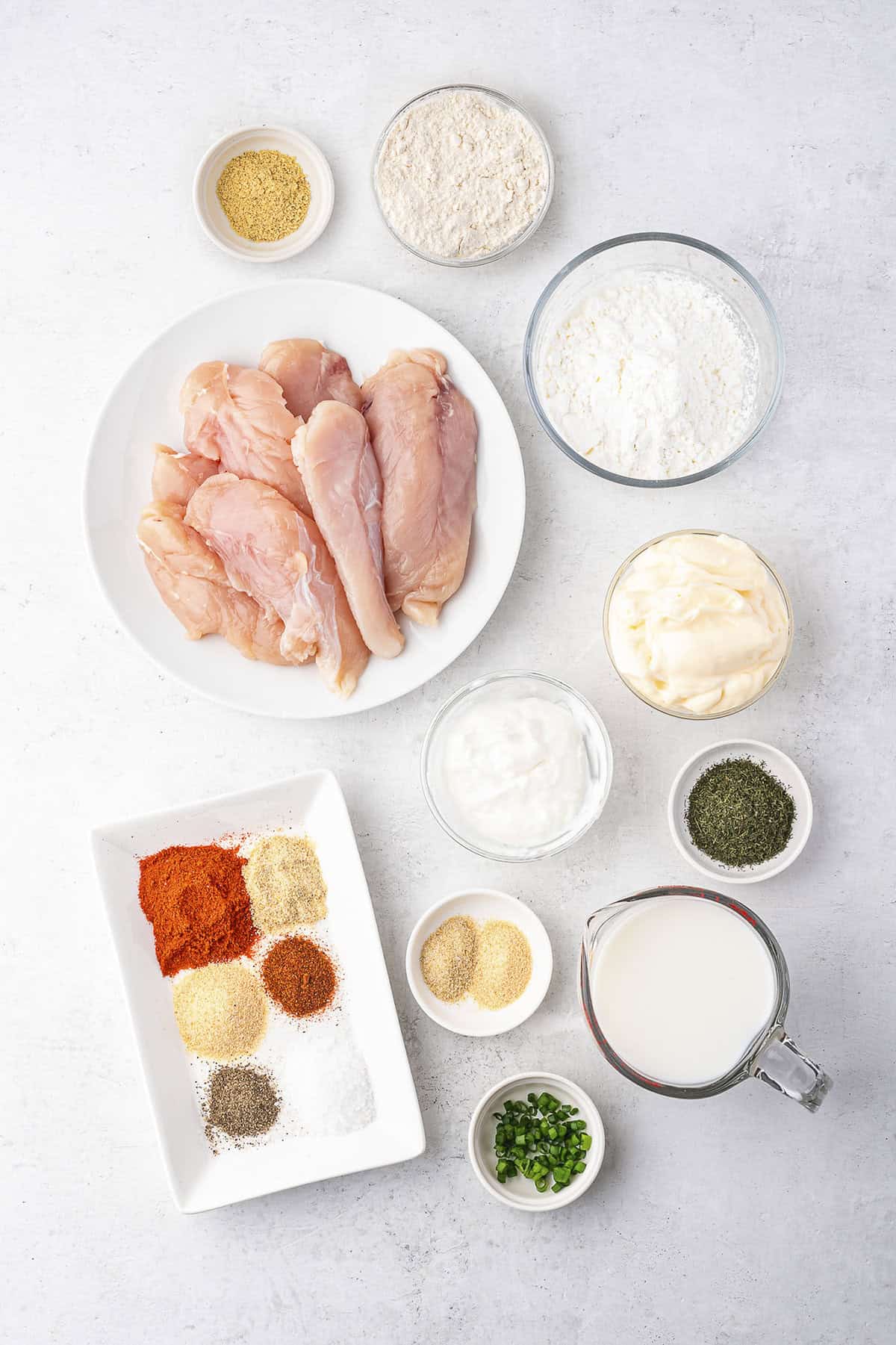 Ingredients for buttermilk chicken tenders and homemade ranch in bowls on counter.