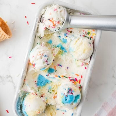 Birthday cake ice cream in metal loaf pan with scoop.