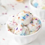 Bowl full of ice cream scoops topped with sprinkles.