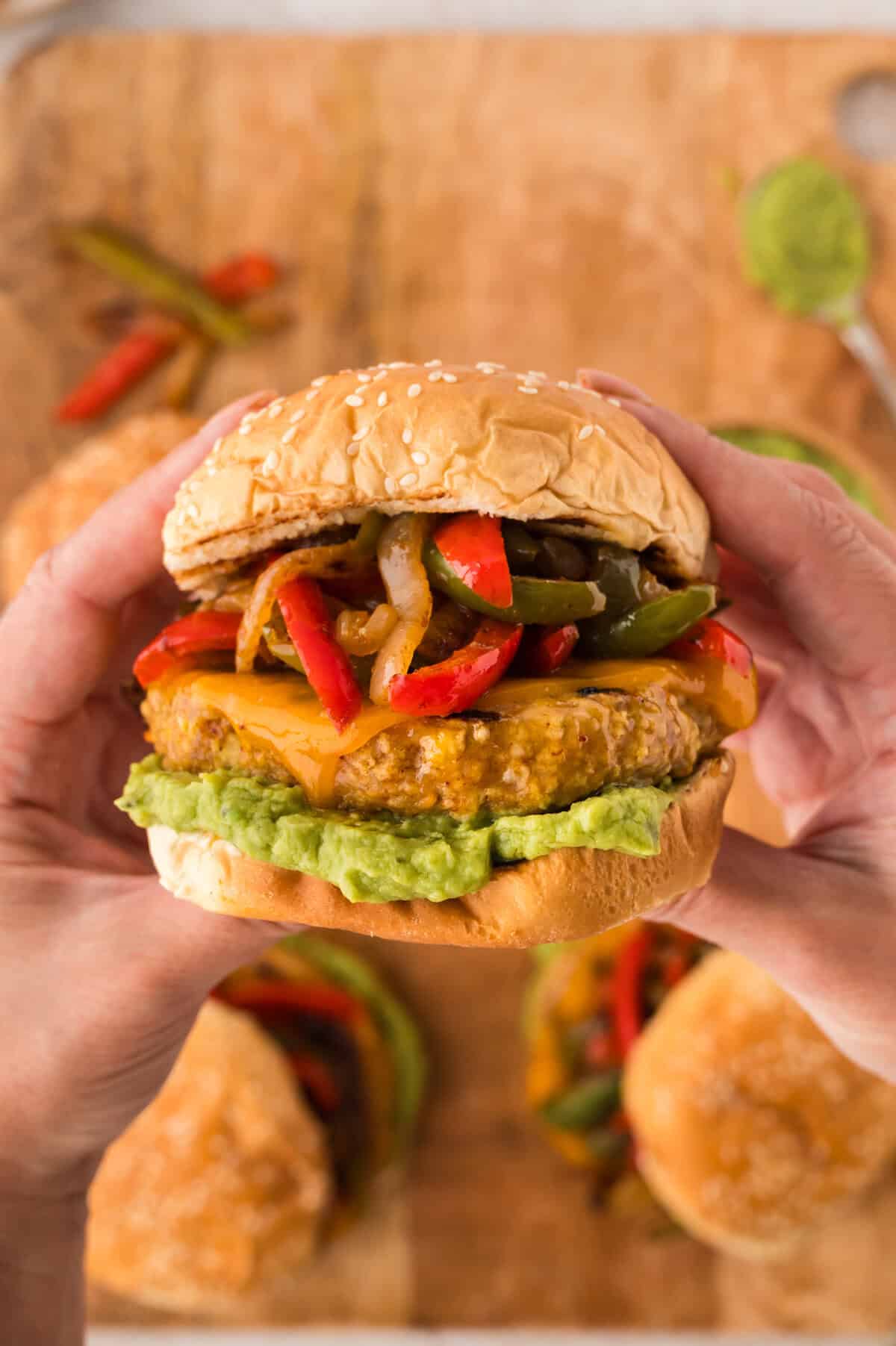 Hands holding a chicken fajita burger.