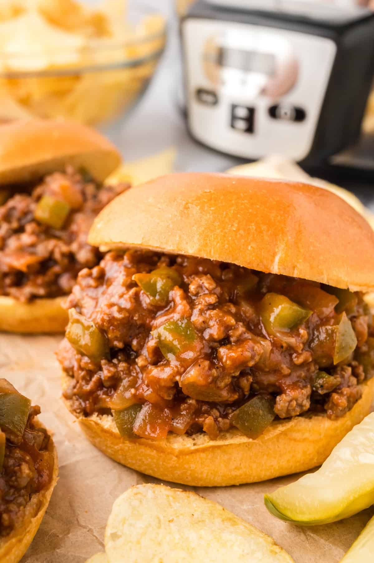 Sloppy joe on a bun in front of a slow cooker.