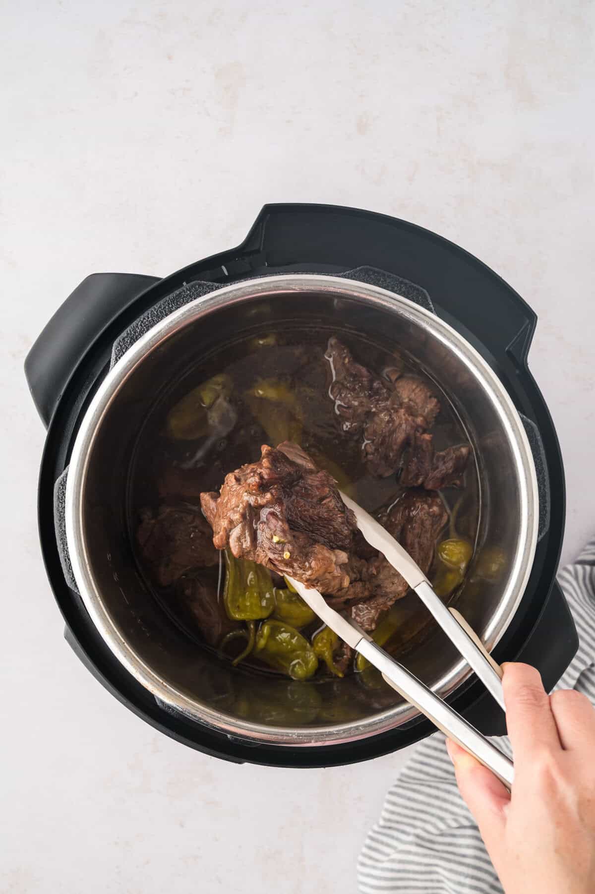 Beef being removed from Instant Pot.
