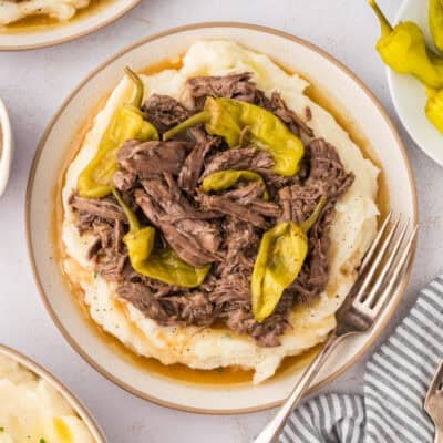 Instant Pot Mississippi roast on plate full of mashed potatoes.