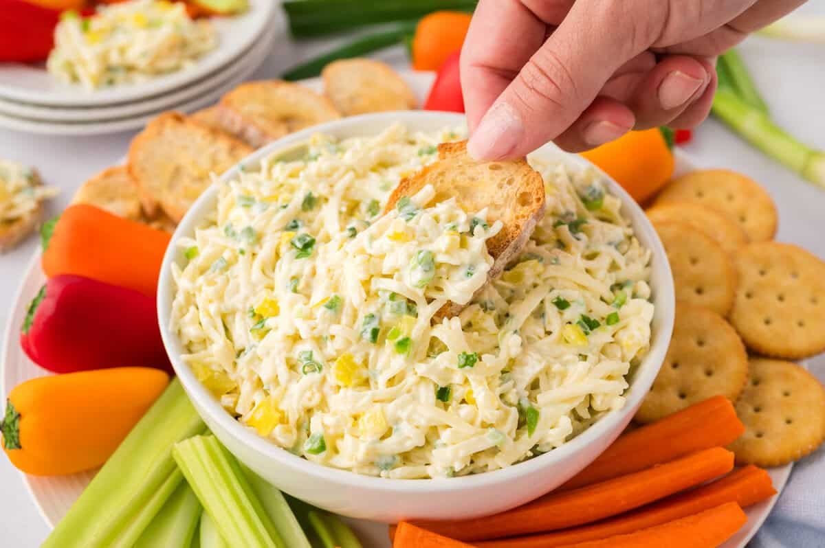Hand scooping a crostini into cheese slaw.