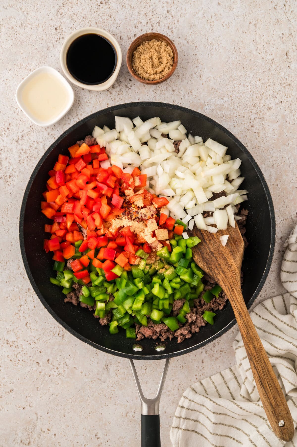 Peppers and onions in skillet with ground beef.