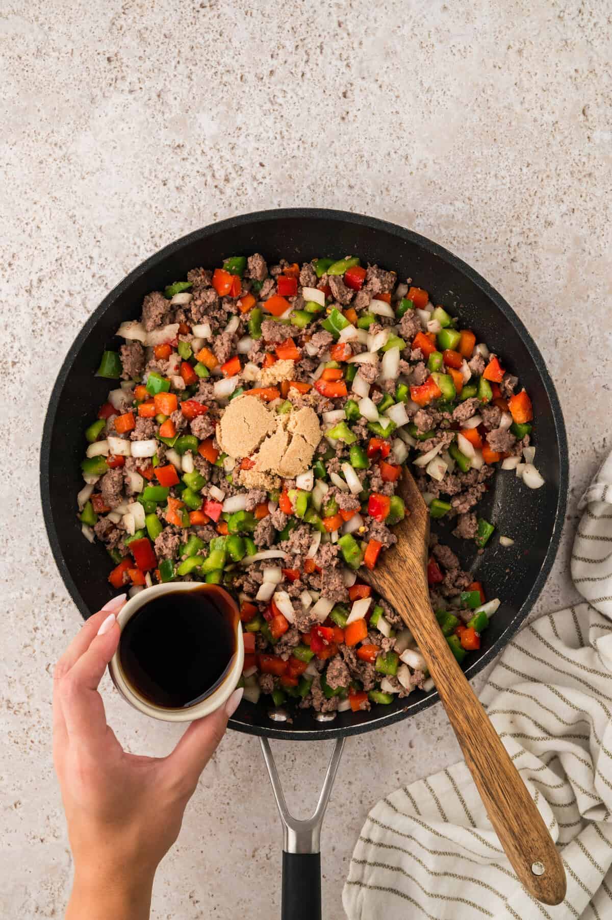 Sauce being poured over beef and peppers.