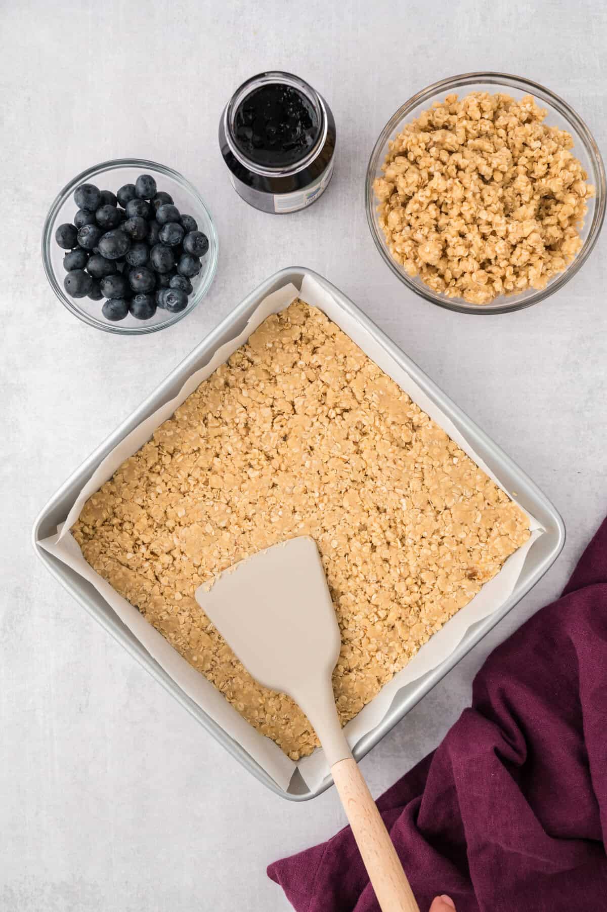 Crumb mixture being pressed into baking dish.
