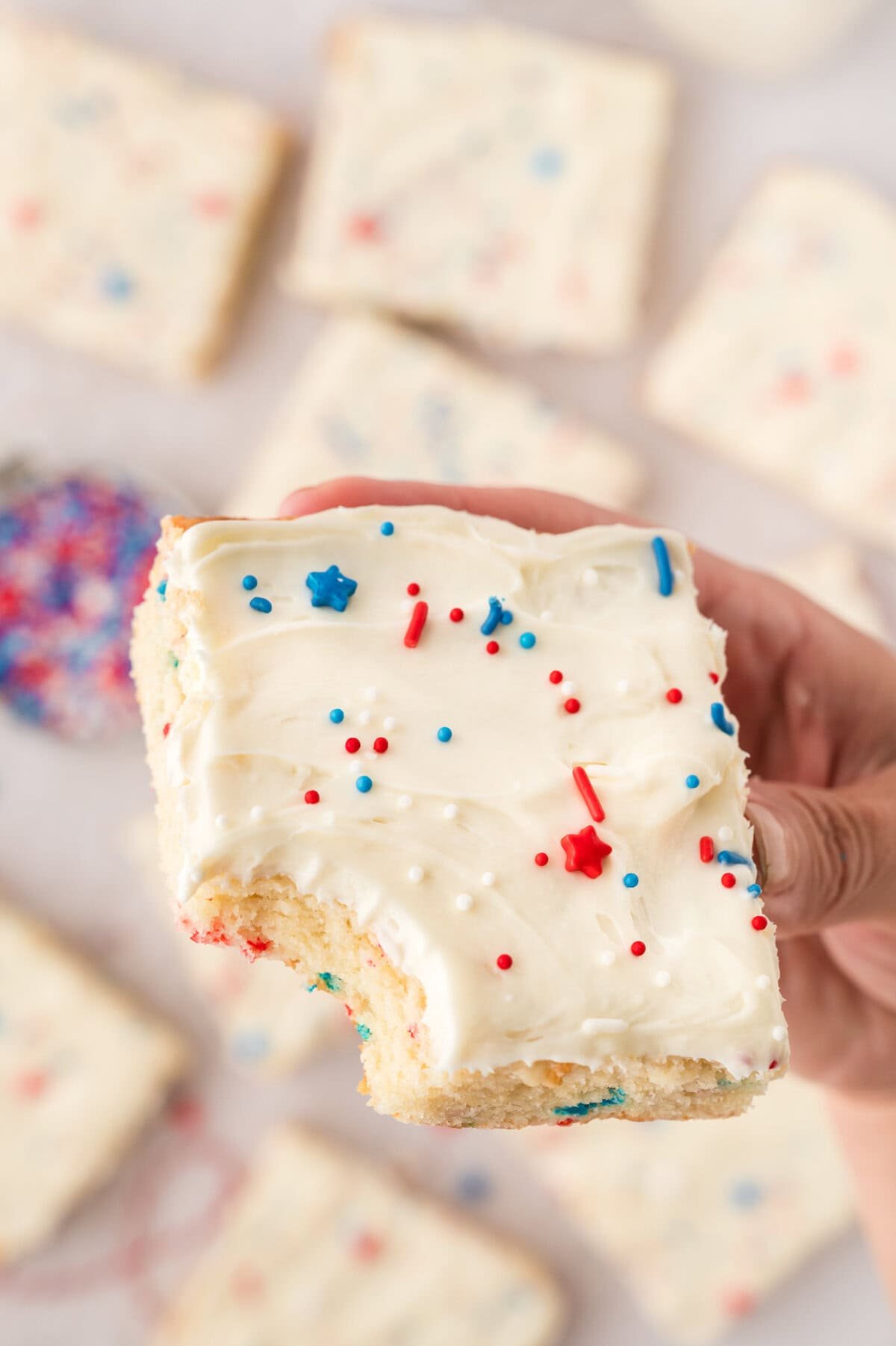 Hand holding a sugar cookie bar topped with red, white, and blue sprinkles.