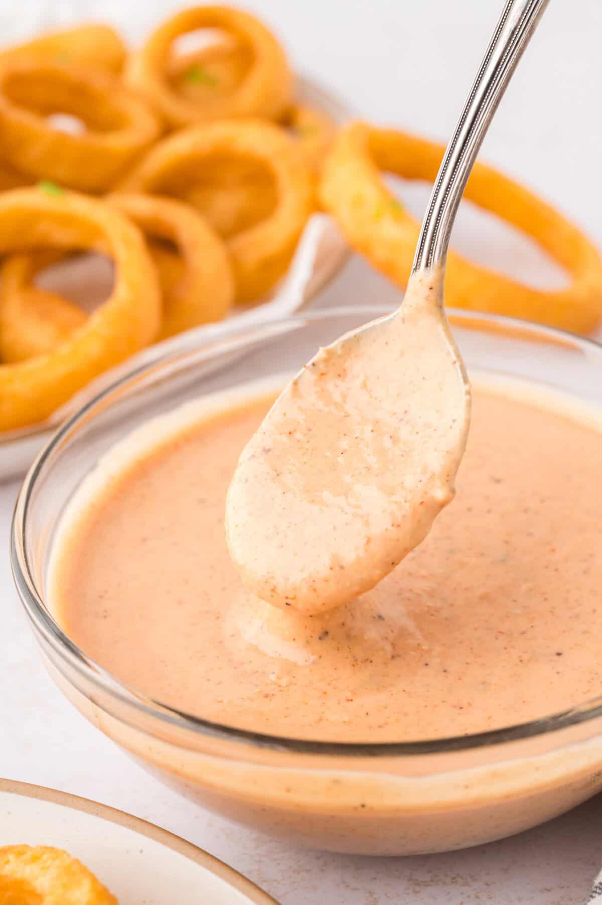 Onion ring sauce dripping off spoon.