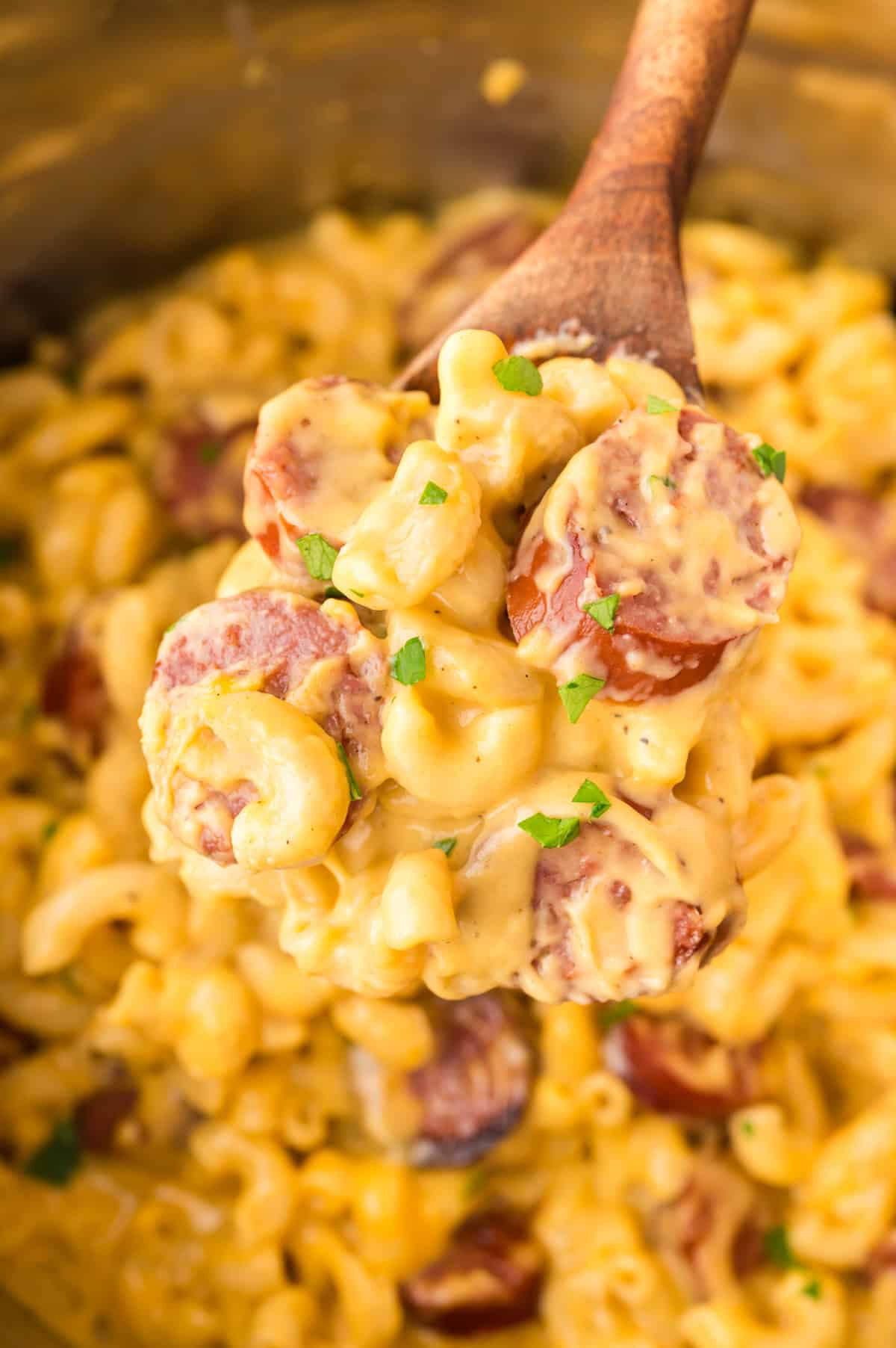 Smoked sausage mac and cheese in Instant Pot on wooden spoon.