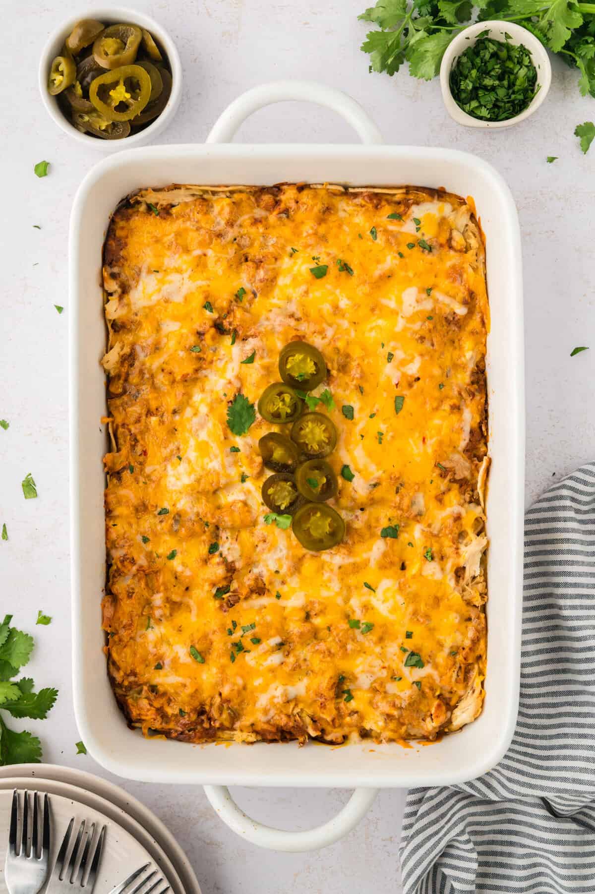 Baked sour cream chicken enchilada casserole in white casserole dish.