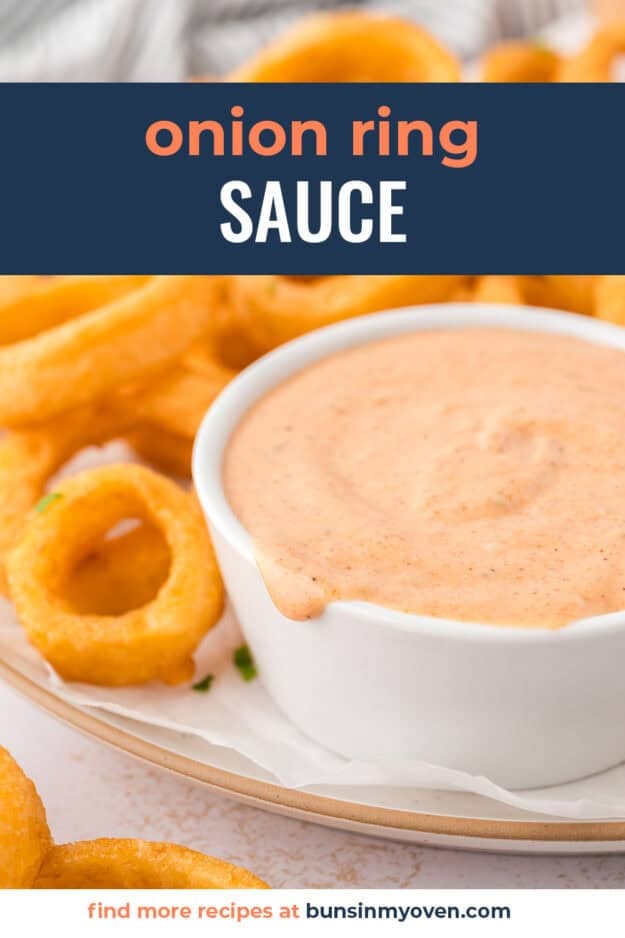 Pink onion ring sauce in white bowl on plate of onion rings.