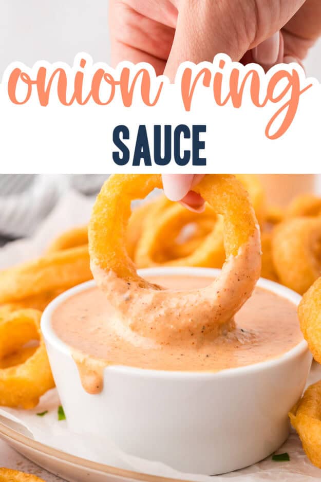 Hand dipping an onion ring in sauce.