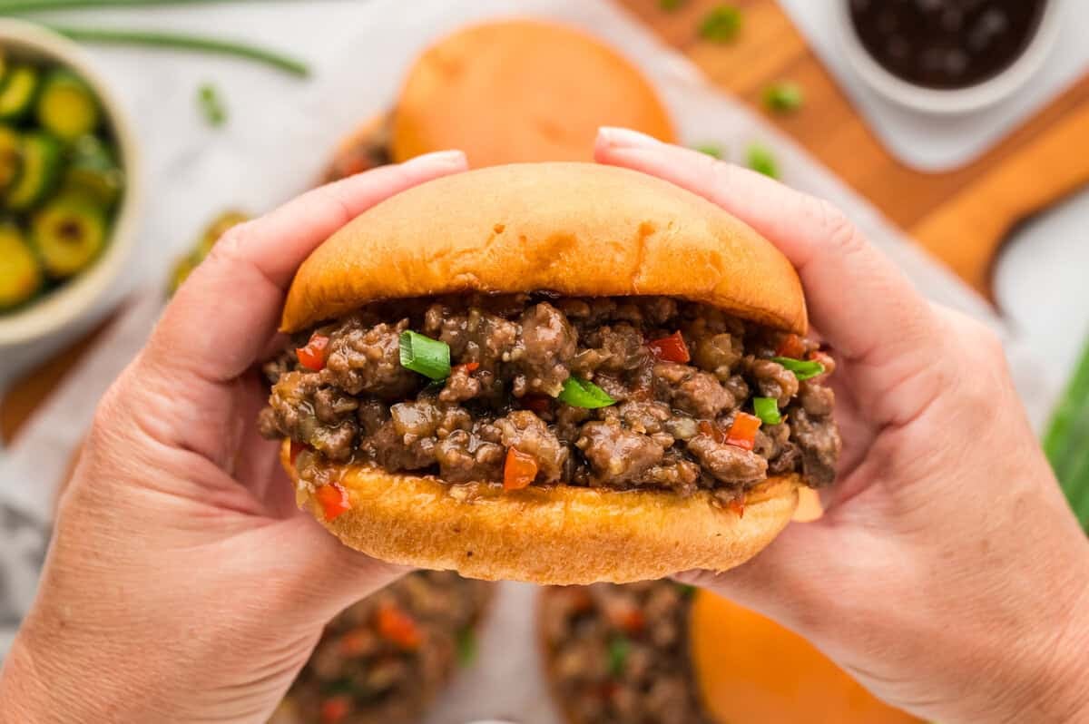 Hand holding a Korean BBQ sloppy joe sandwich.