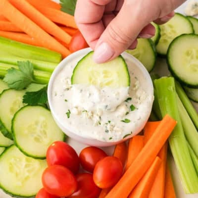 Carrot being dipped in blue chees dressing.