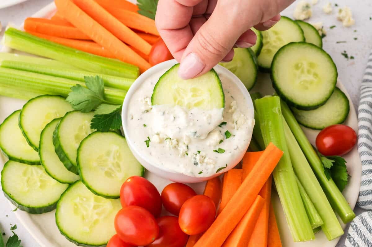 Carrot being dipped in blue chees dressing.