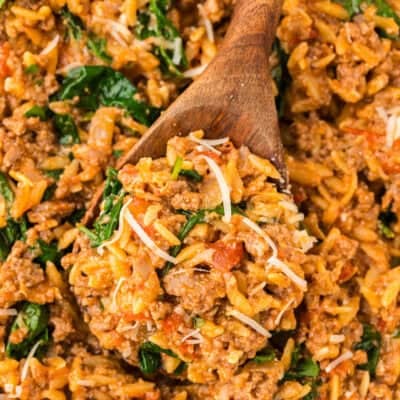 Ground beef and orzo on wooden spoon.