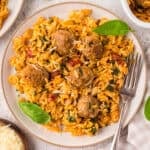 Creamy tomato baked orzo with meatballs on small white plate.