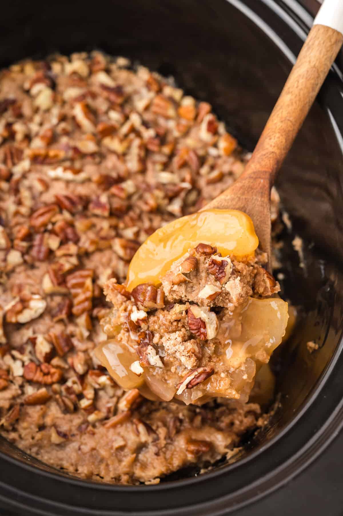 Crockpot apple dump cake on wooden spoon.