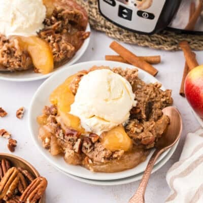 White plate topped with crockpot apple dump cake and a scoop of vanilla ice cream.
