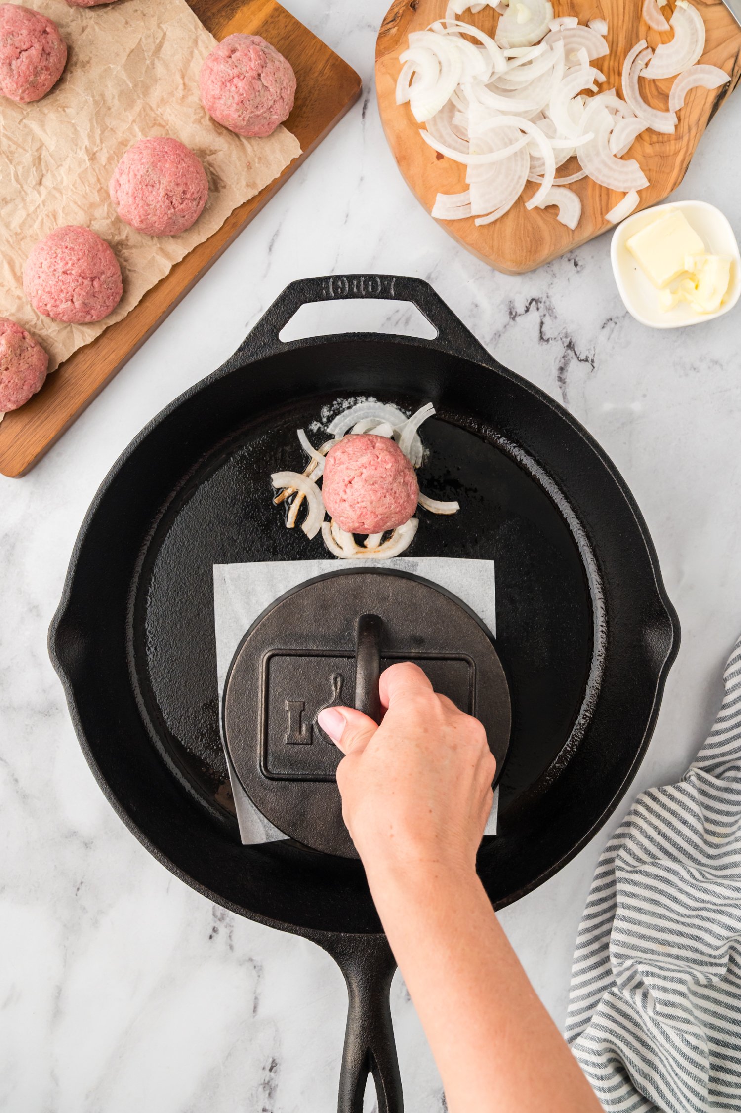 Burgers being smashed in cast iron skillet