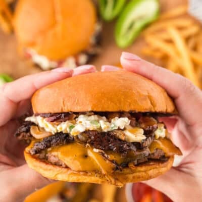 Hands holding a jalapeno popper smash burger.