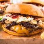 Jalapeno burger on bun on wooden cutting board with fries.