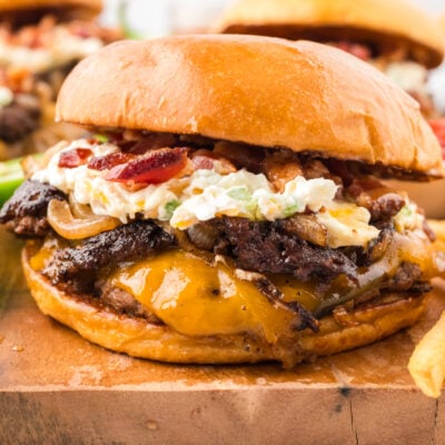 Jalapeno burger on bun on wooden cutting board with fries.