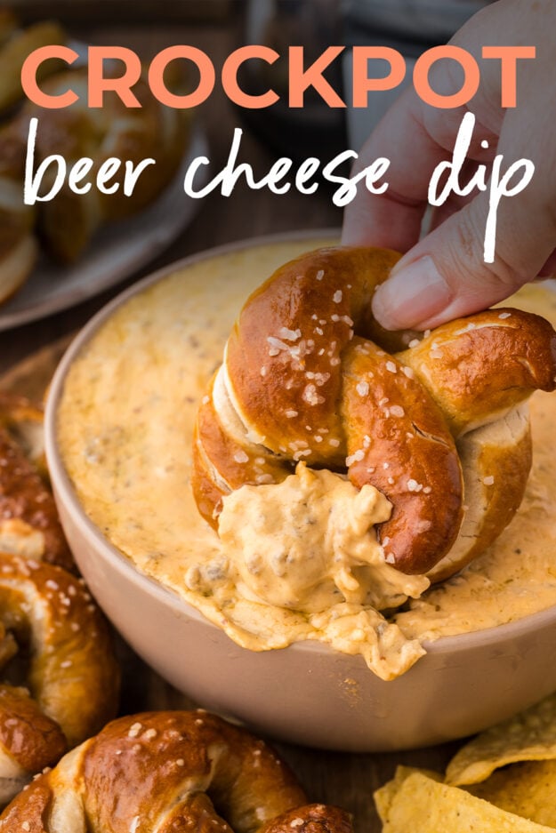 Homemade soft pretzel being dipped in hot sausage beer cheese dip.