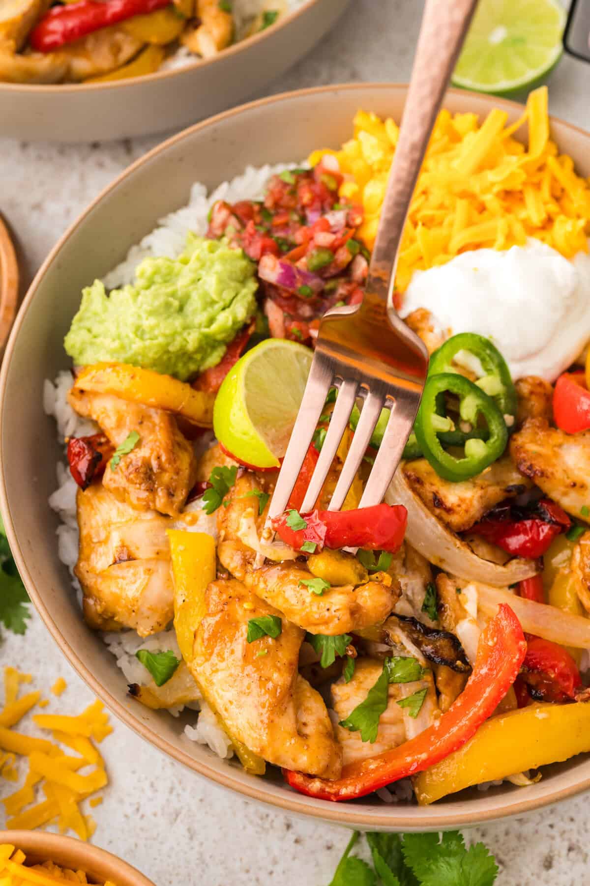 Bowl full of chicken fajita mixture with fork.