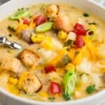 Bowl full of cheeseburger soup recipe topped with tomatoes and pickles.