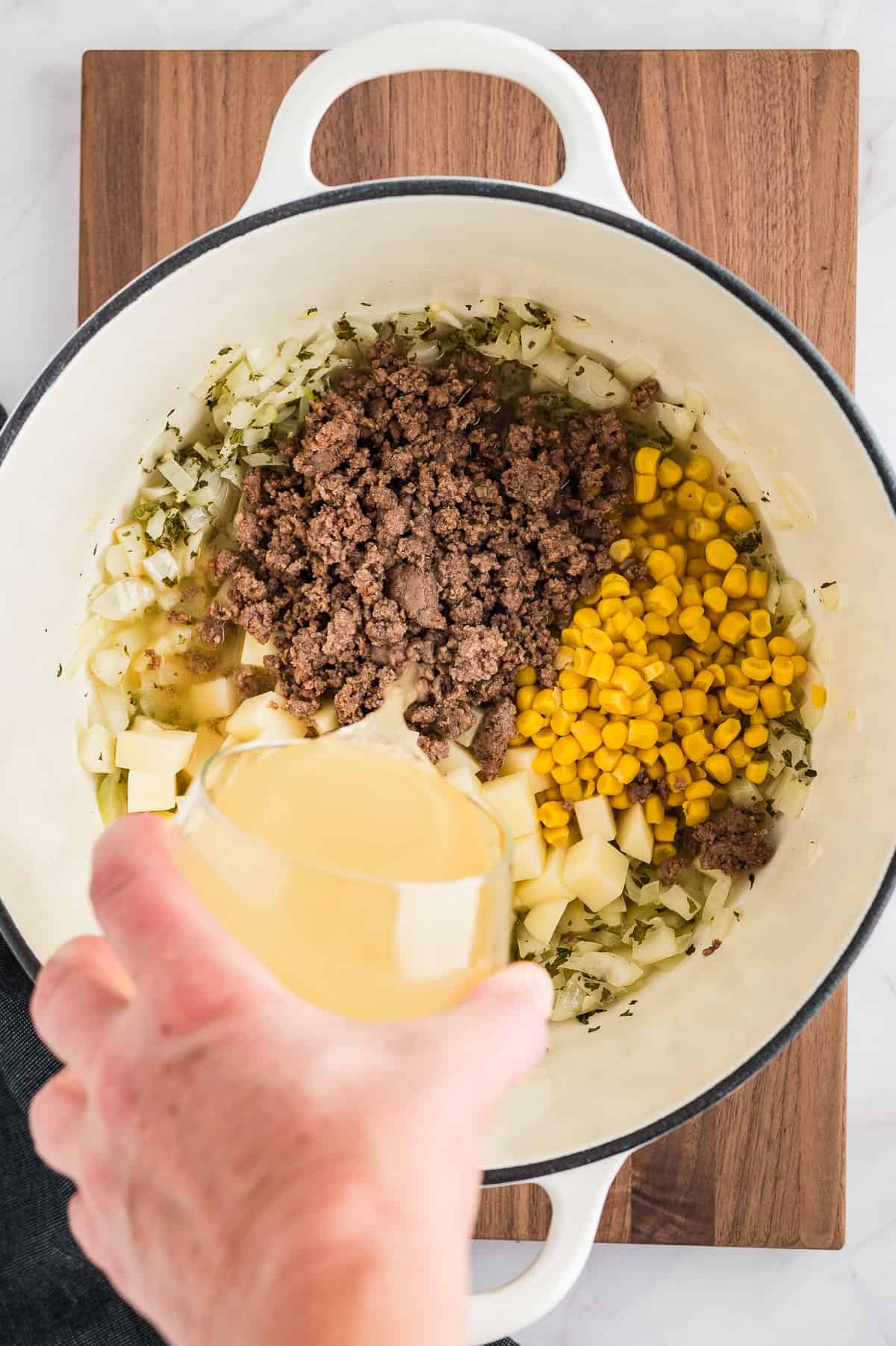 Corn and stock in pot with beef and potatoes.