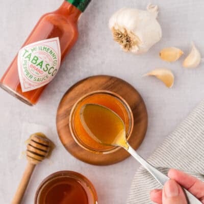 Hot honey sauce on a spoon over a jar.