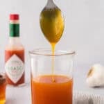 Sauce dripping off spoon into jar.