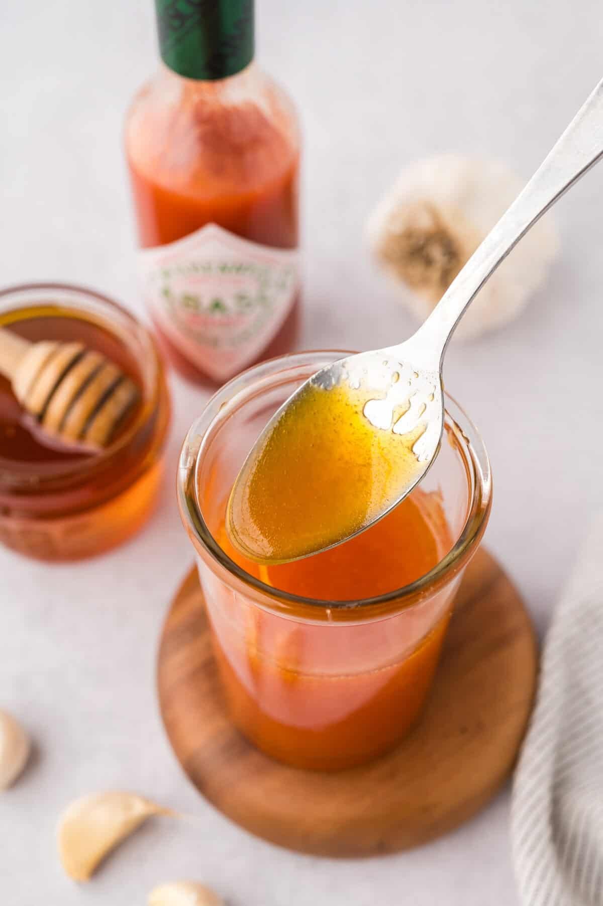 hot honey sauce on spoon over a jar.