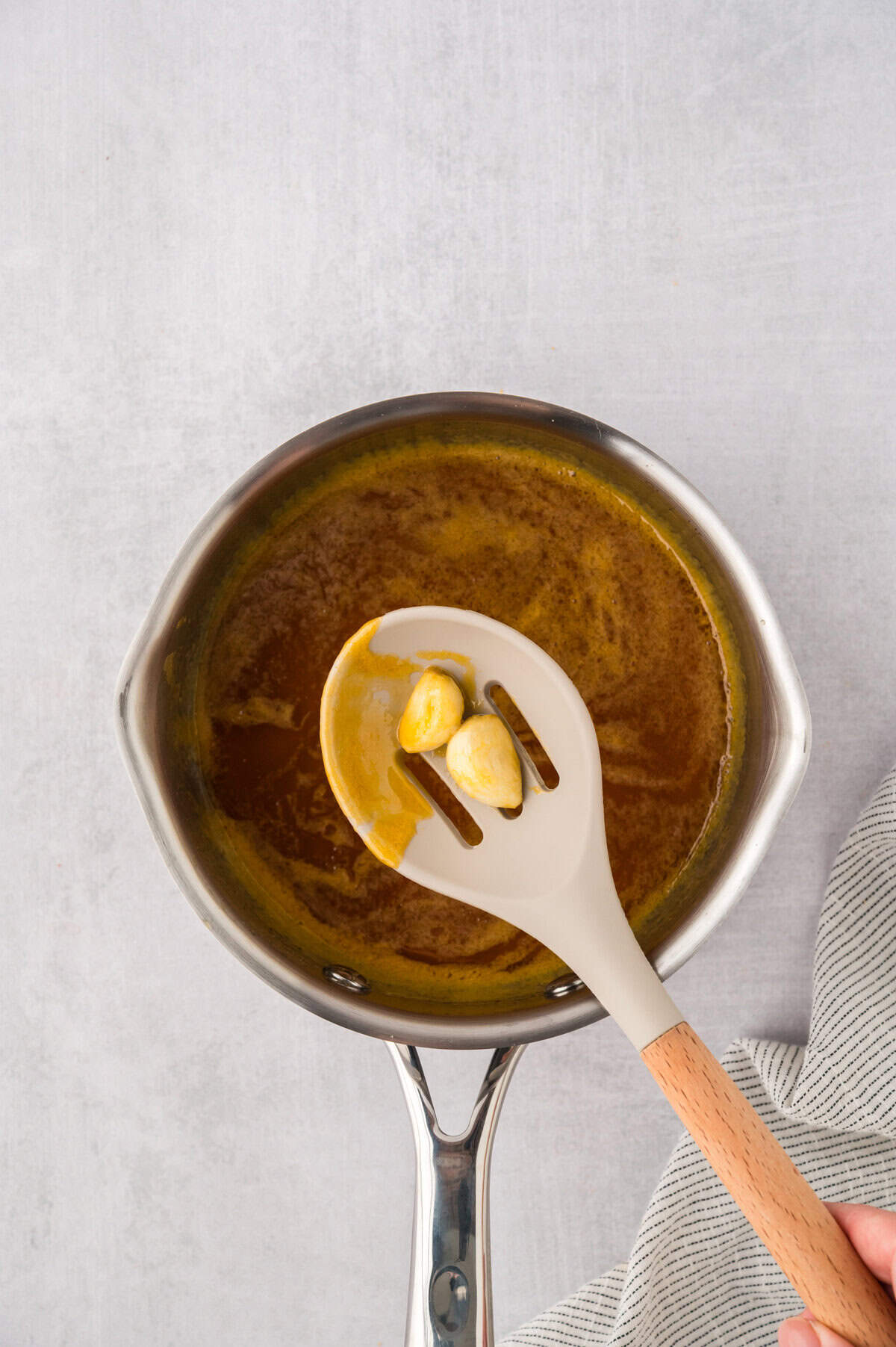 Garlic cloves being removed from hot honey sauce.