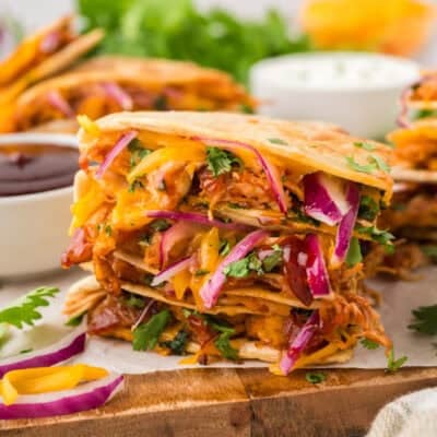 Stack of bbq chicken quesadilla wedges on wooden board.