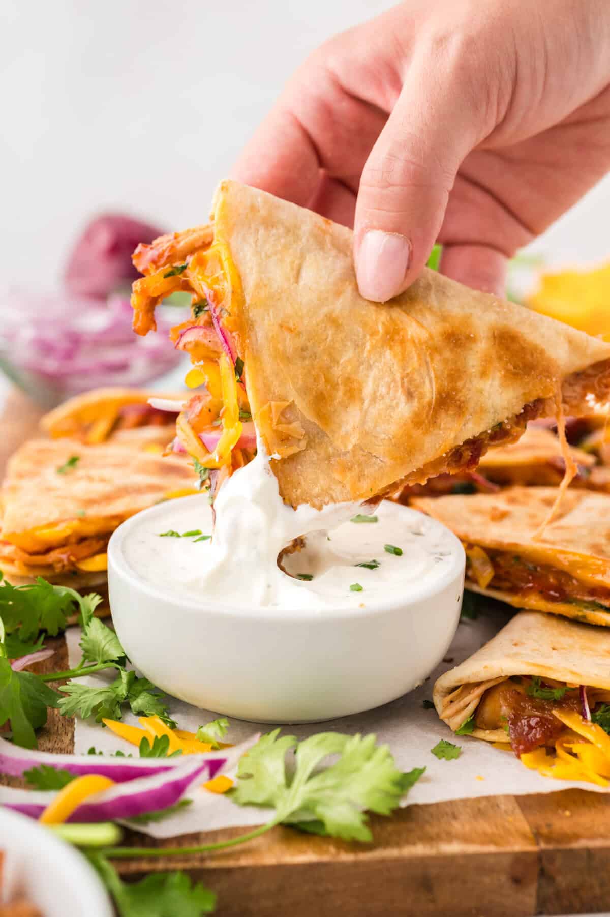 BBQ chicken quesadilla being dipped in ranch dressing.