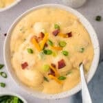 Bowl full of loaded gnocchi soup recipe topped with cheese and bacon.
