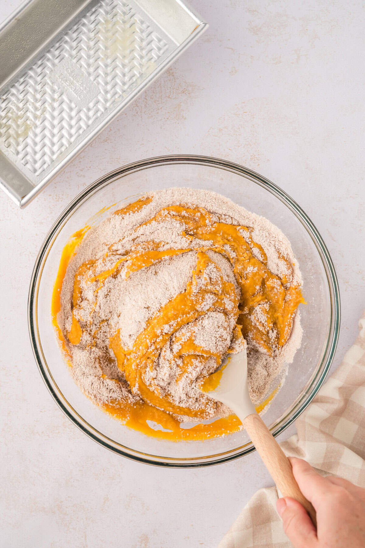 Batter for pumpkin bread being mixed in a glass bowl.