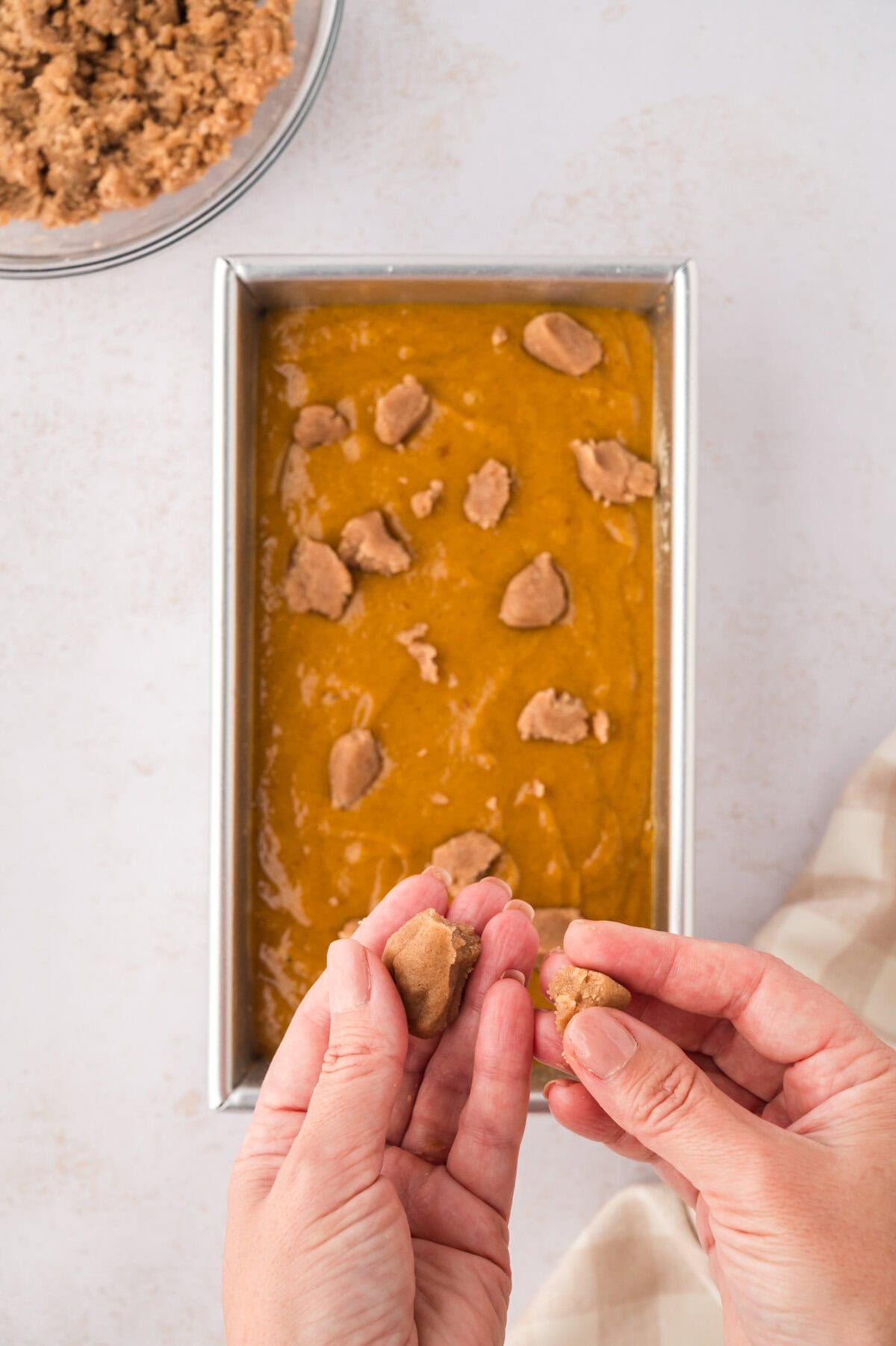Streusel chunks being placed over pumpkin bread