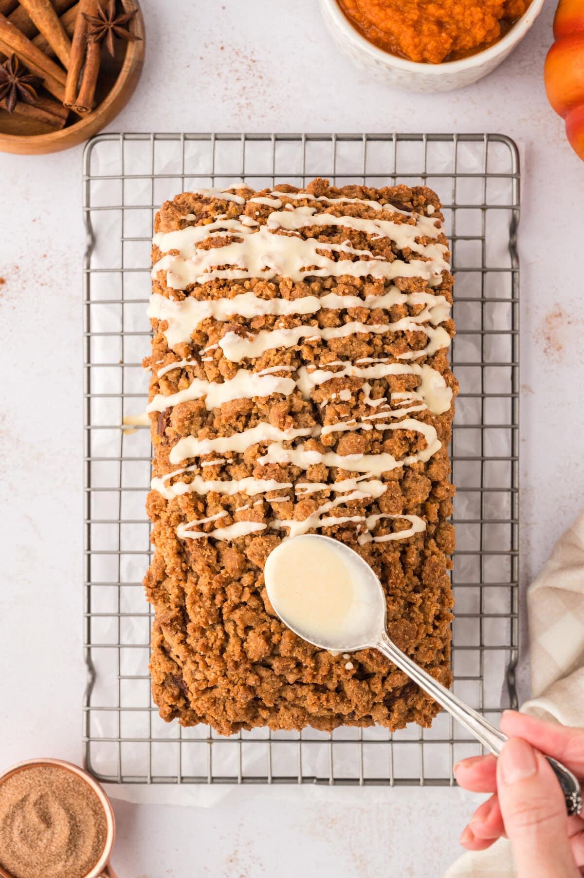 Browned butter glaze being drizzled over pumpkin streusel bread.