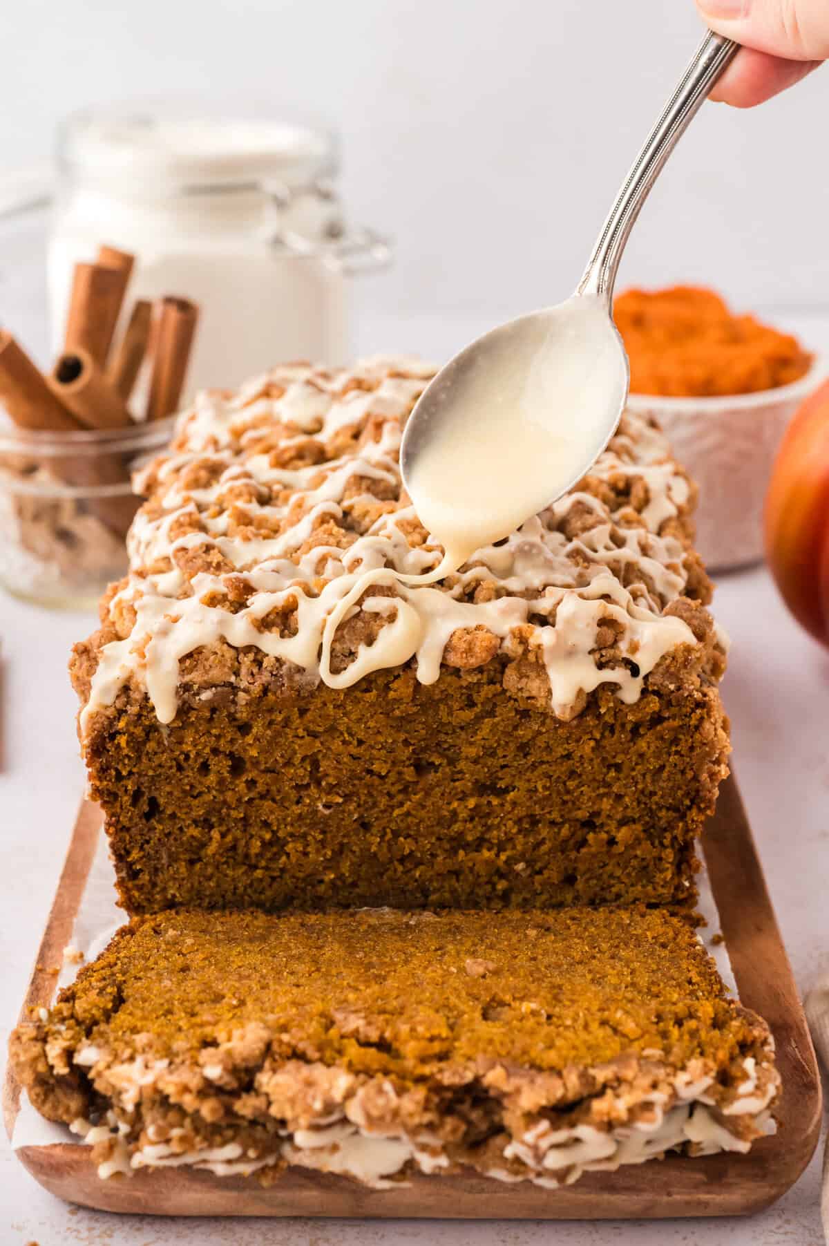 Browned butter glaze being drizzled over pumpkin streusel bread.